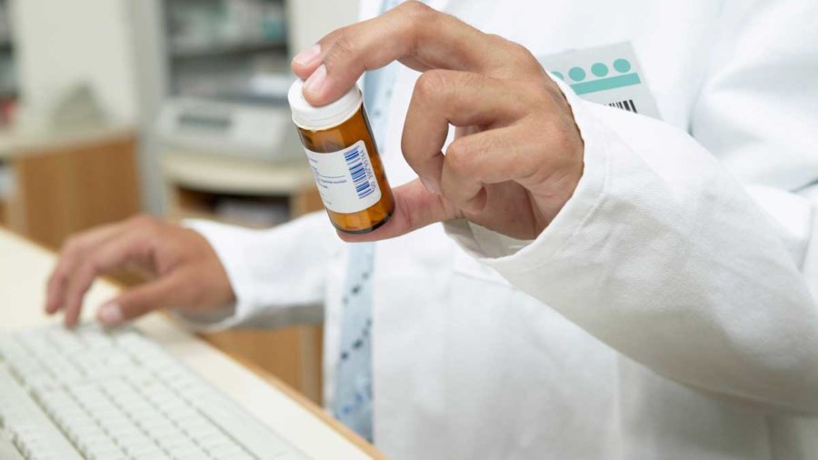 Close up of male pharmacist holding prescription bottle