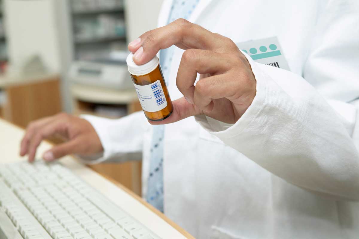 Close up of male pharmacist holding prescription bottle